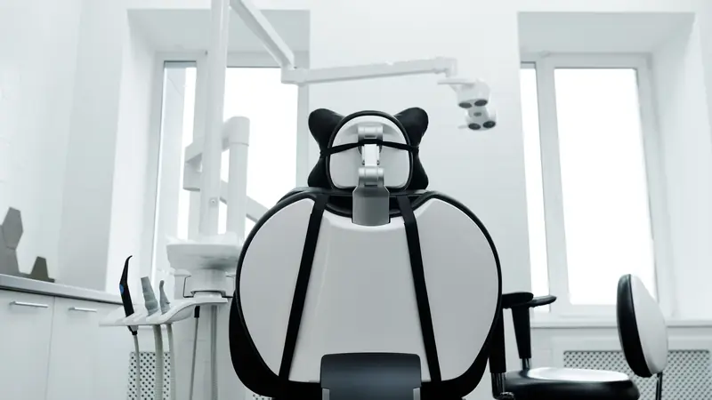 Fauteuil de soins dentaires vide vu de dos dans un cabinet blanc et lumineux