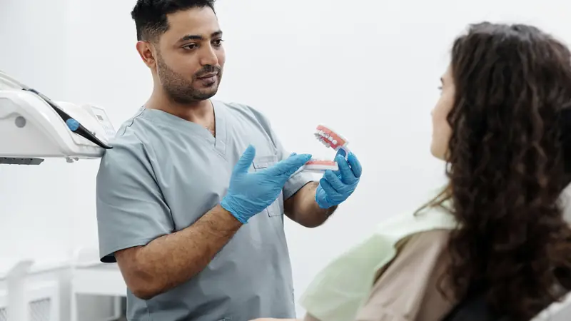 Dentiste qui montre un modèle de mâchoire à une patiente
