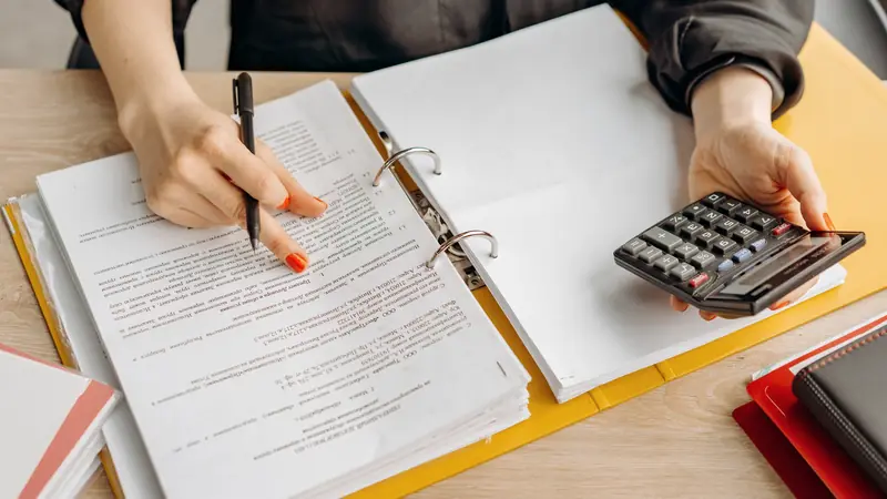 Personne qui compare des documents d'assurance à une table avec une calculatrice
