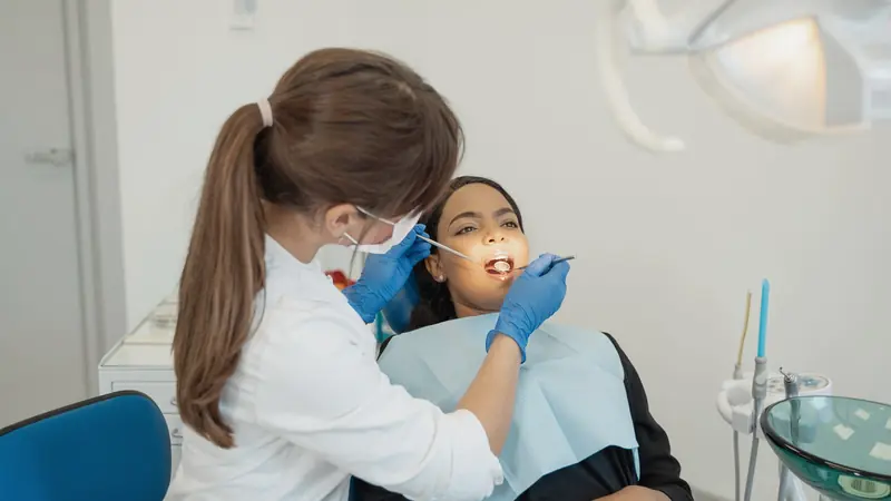 Dentiste qui examine la bouche d'une patiente au cabinet