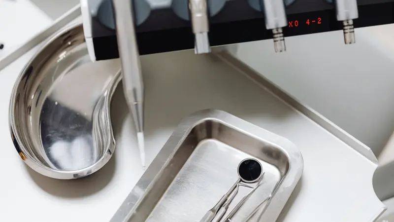 Plateau en inox avec miroir et sondes dentaires sous les instruments rotatifs d'un fauteuil de soins
