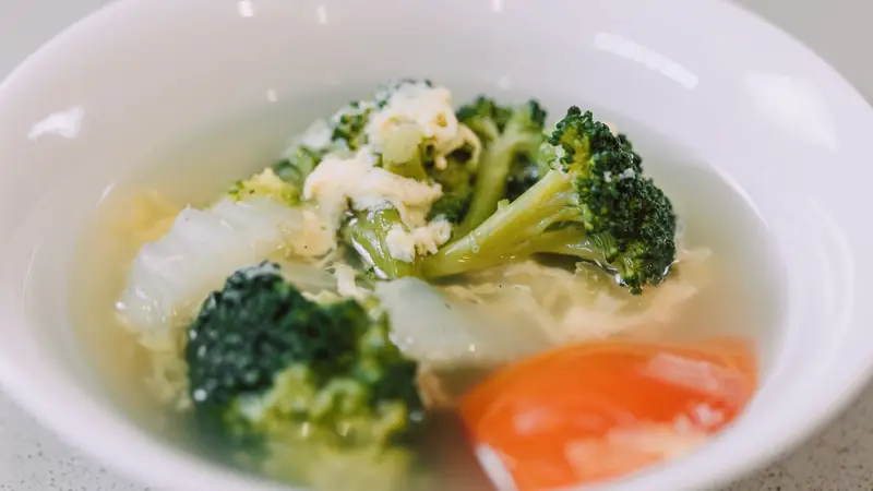 Bol de soupe aux brocolis, chou, œuf et tomate