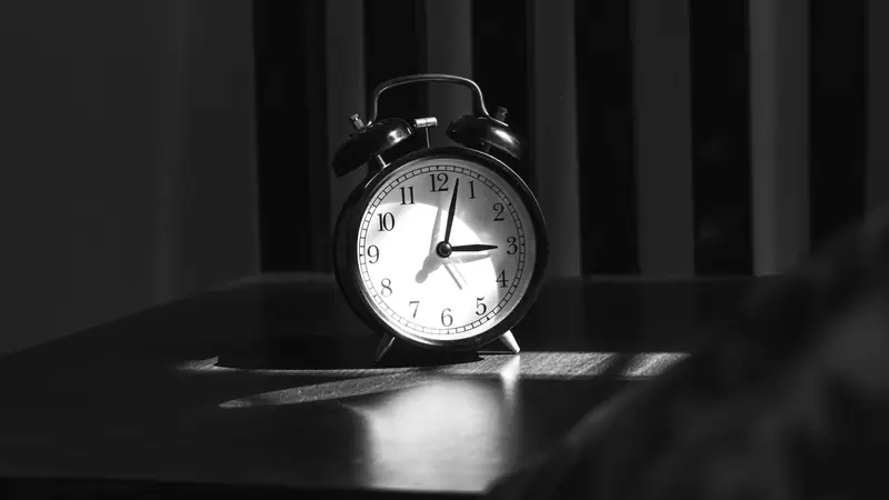 Réveil posé sur une table de nuit dans une chambre sombre