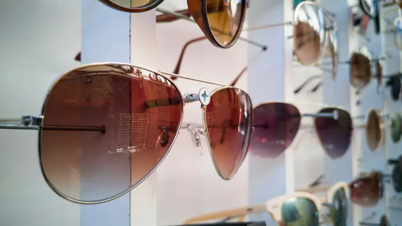 Présentoir de lunettes de soleil aviateur et de montures variées suspendues sur des tiges