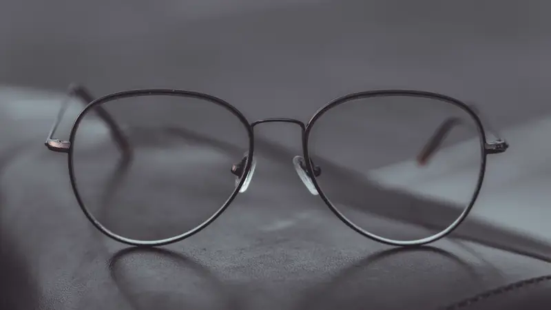 Lunettes de vue à fine monture métallique de forme pantos posées sur une surface en cuir sombre