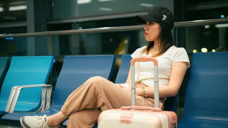 Voyageuse assise dans un aéroport avec sa valise