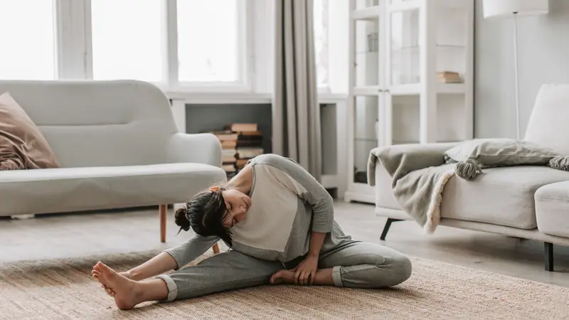 Personne qui fait des étirements sur un tapis dans un salon